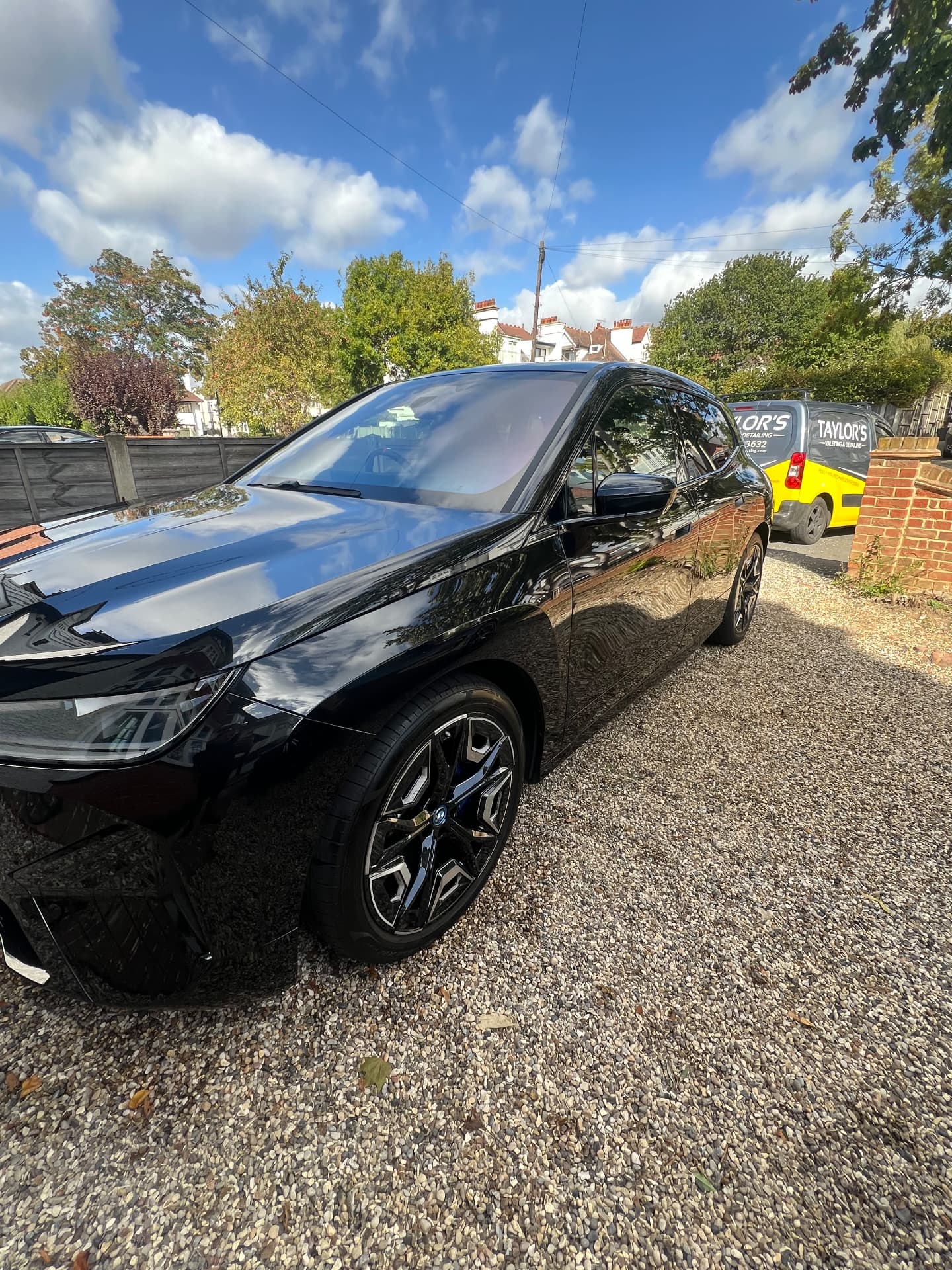 Black BMW iX polished beside the Taylor's valeting van