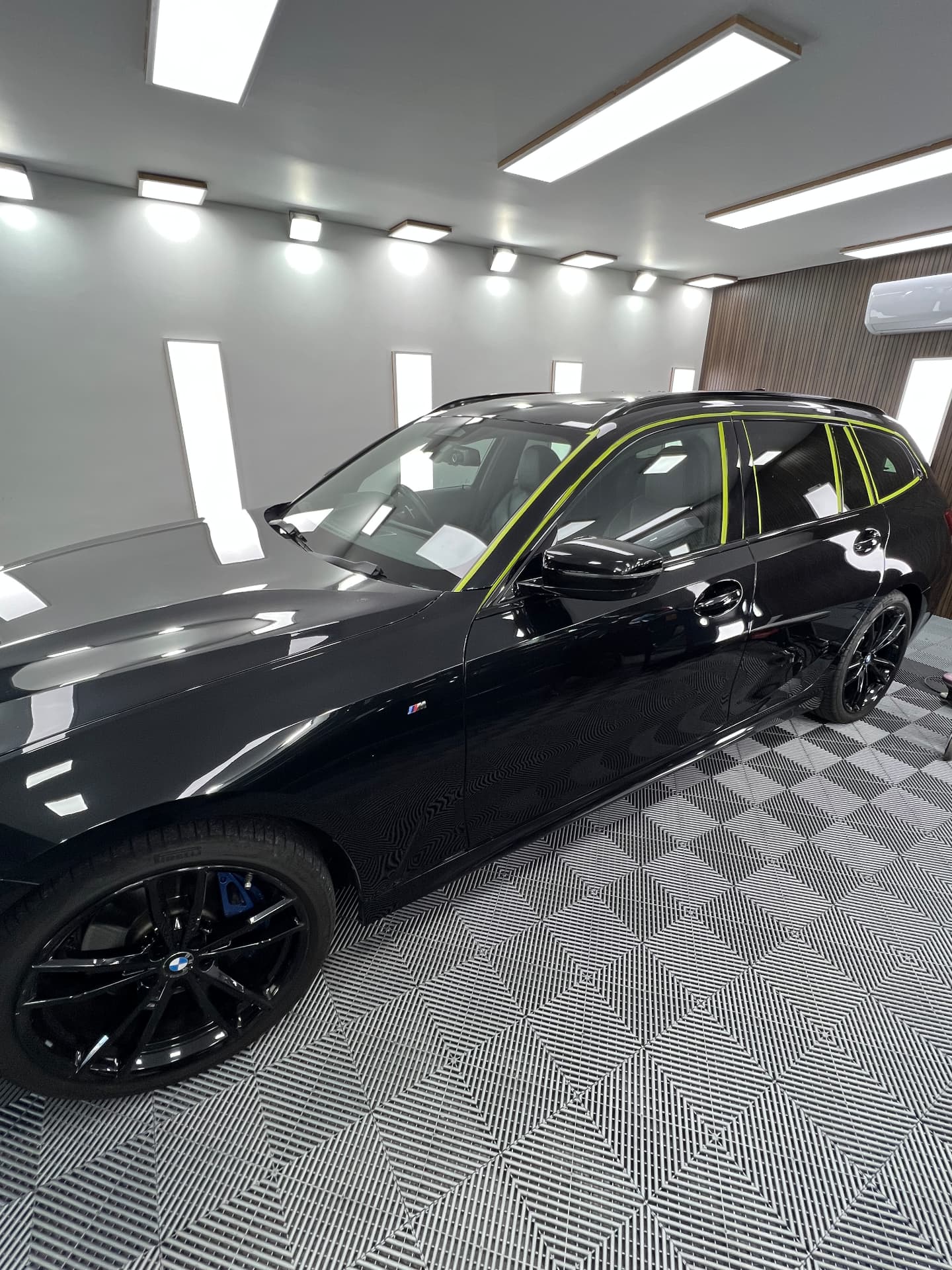 Black BMW 3 Series Touring masked up for machine polishing in the unit
