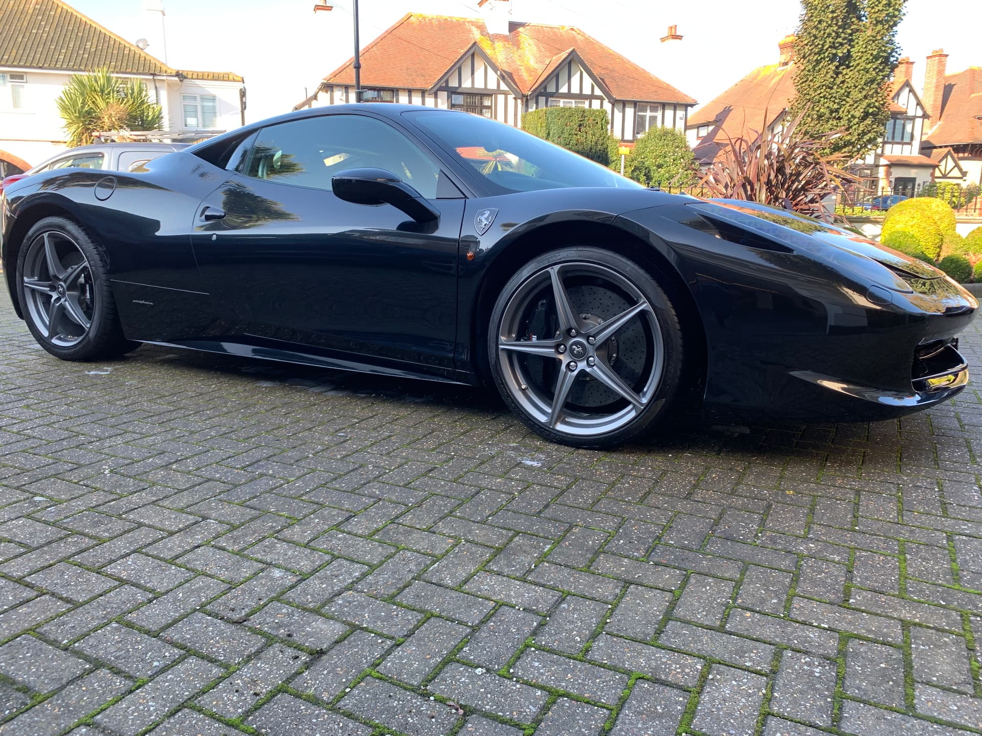 Black Ferrari 458 Italia detailed to a mirror finish on a block driveway