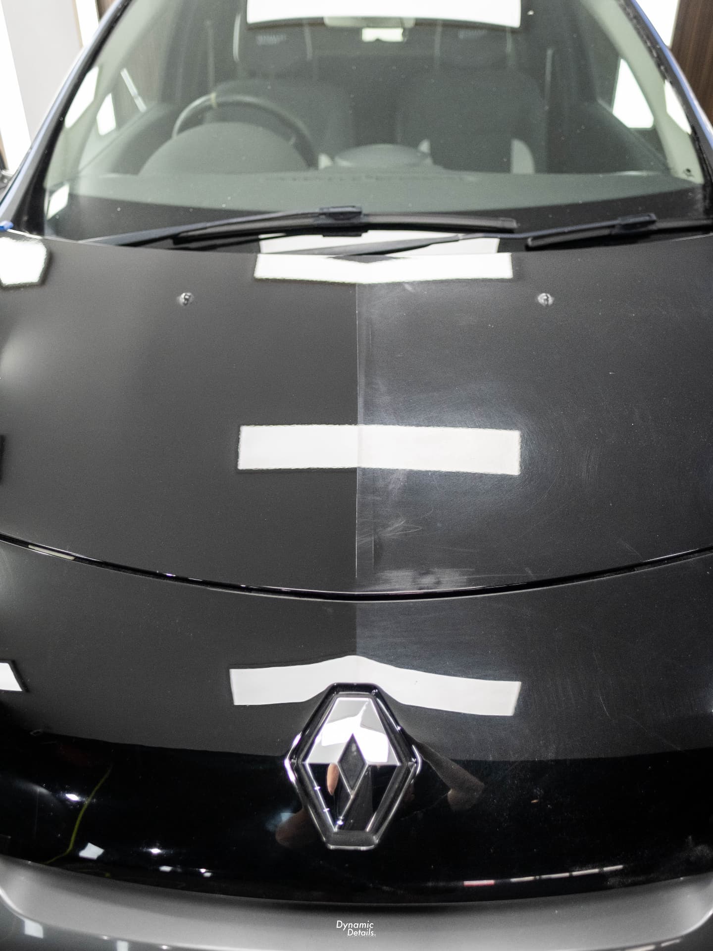 Half-polished black bonnet showing swirl removal after stage paint correction
