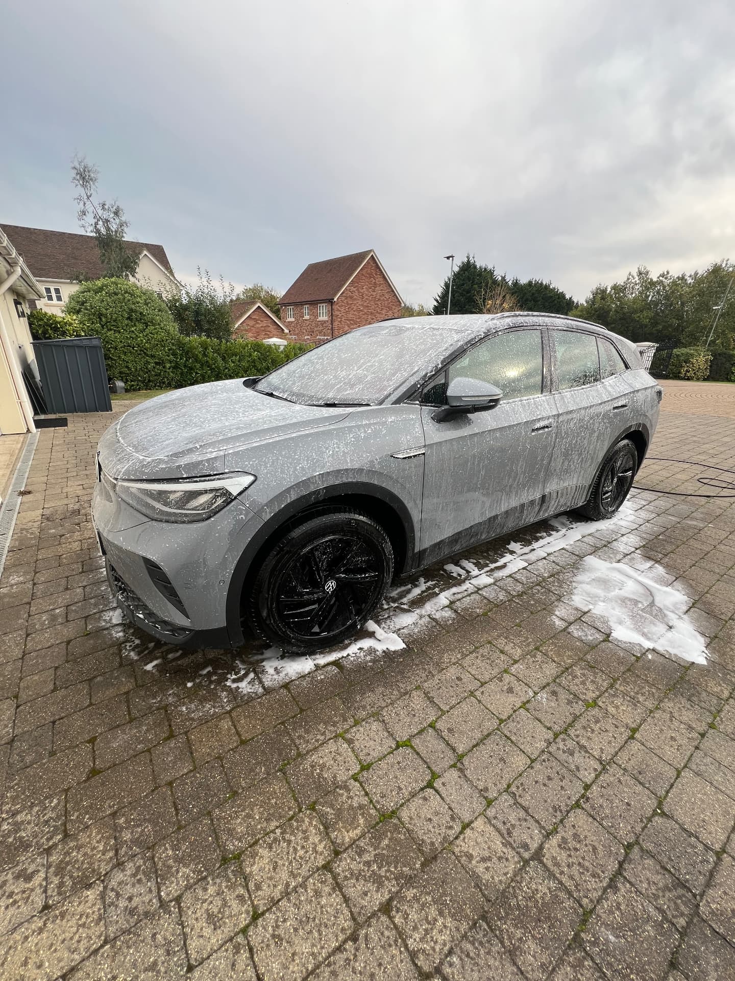 Grey VW ID.4 covered in snow foam during a wash on a driveway