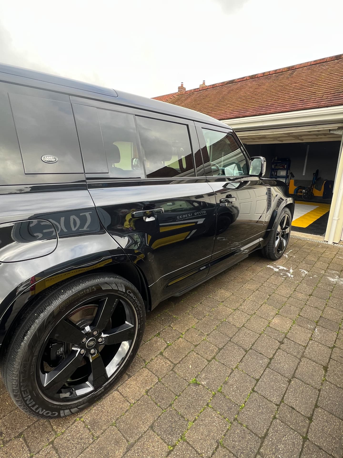 Black Land Rover Defender gleaming on a driveway after a full valet
