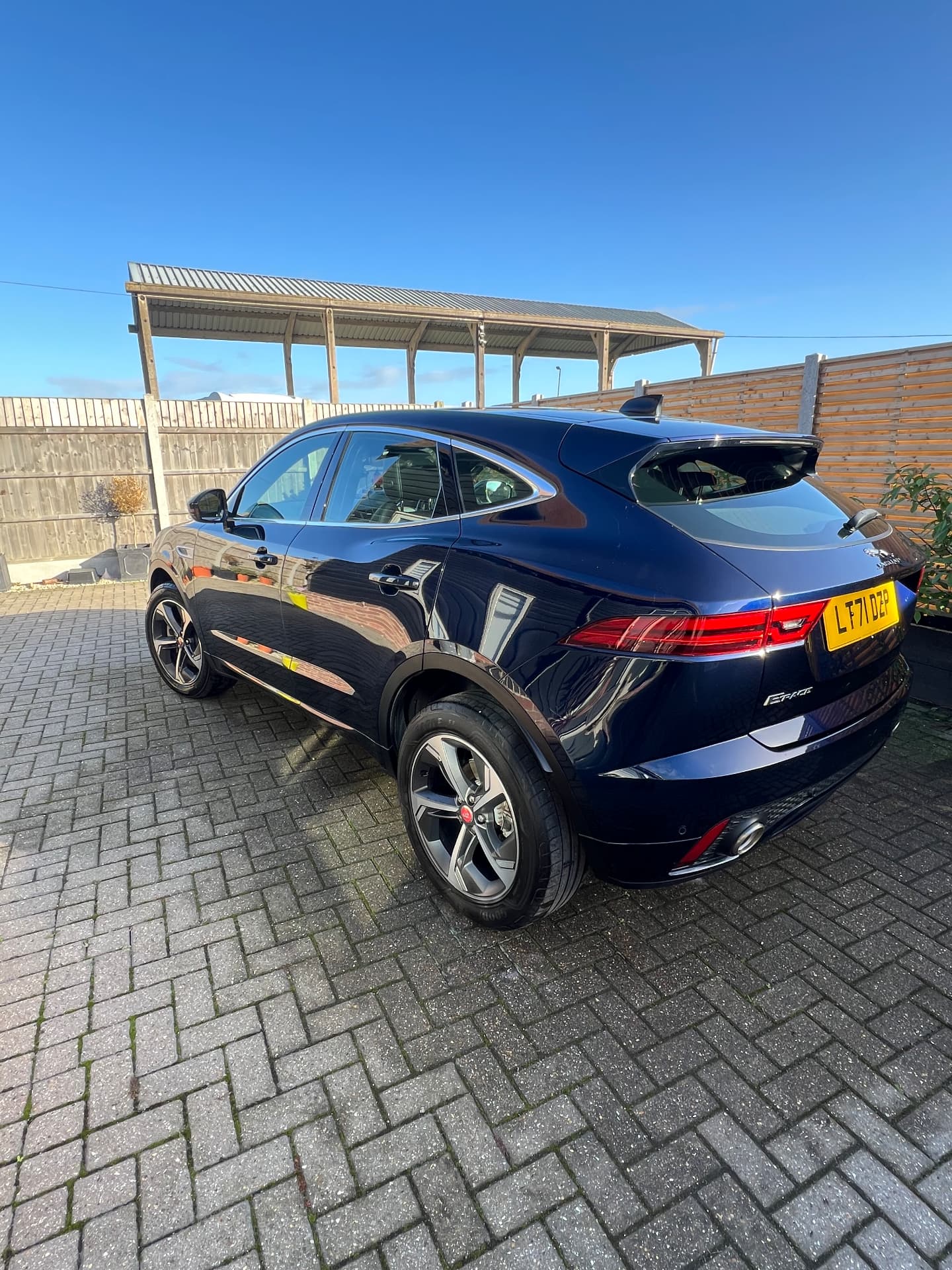 Dark blue Jaguar E-Pace with a mirror-gloss finish on a block-paved driveway