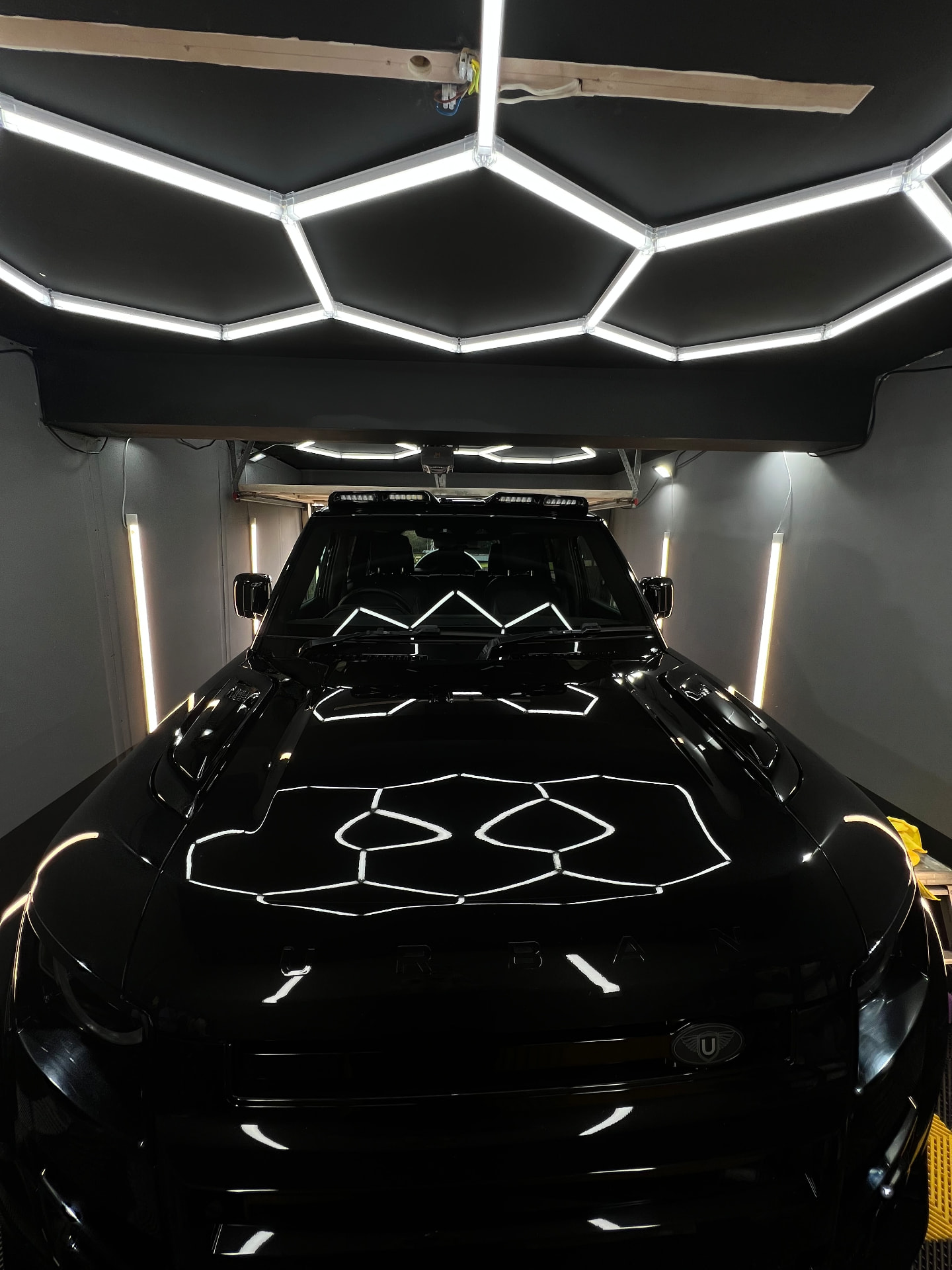 Black Urban Land Rover Defender reflecting hex lighting after a gloss detail