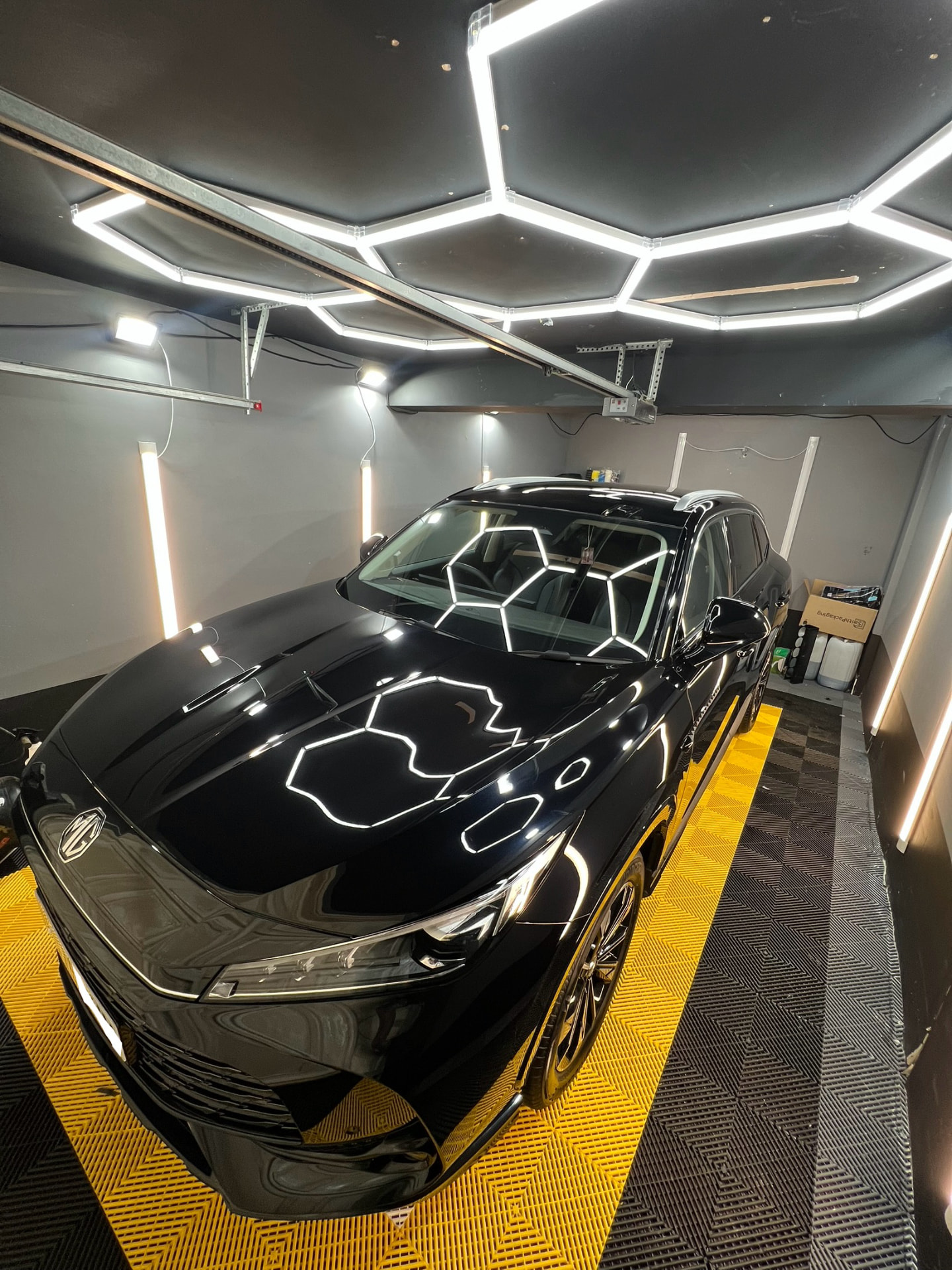 Black MG SUV with a mirror finish under hex lighting in the unit