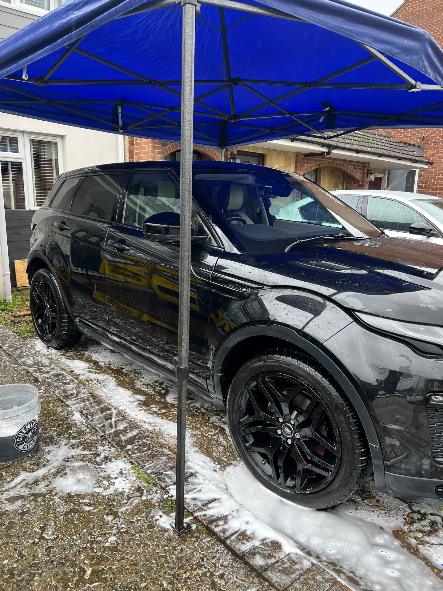 Black Range Rover Evoque being snow-foamed under the valeting canopy