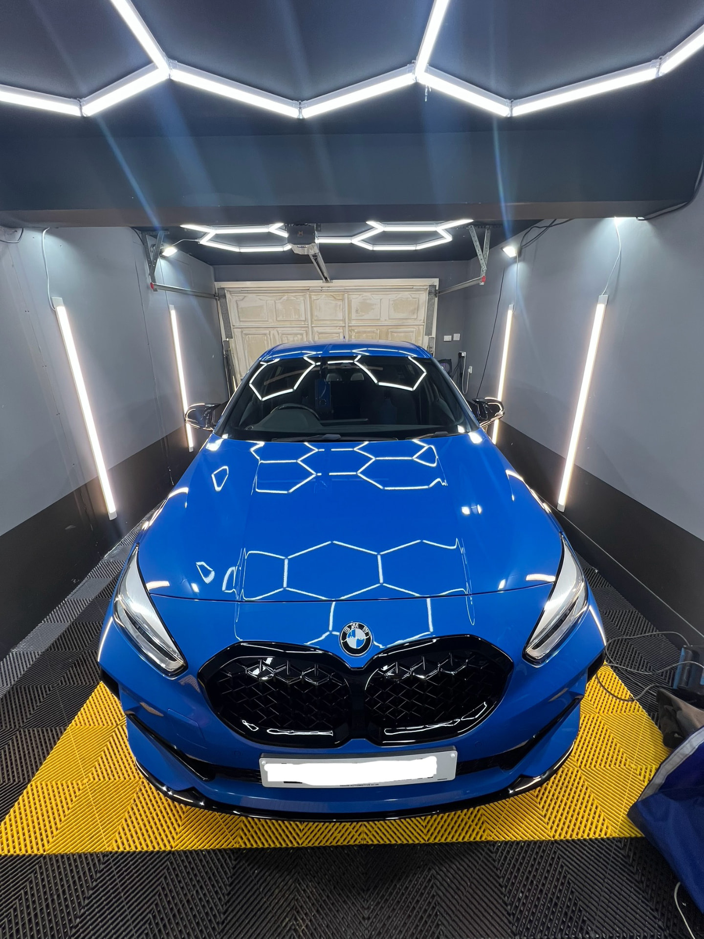 Blue BMW 1 Series gleaming under hex lighting in the Daws Heath detailing unit