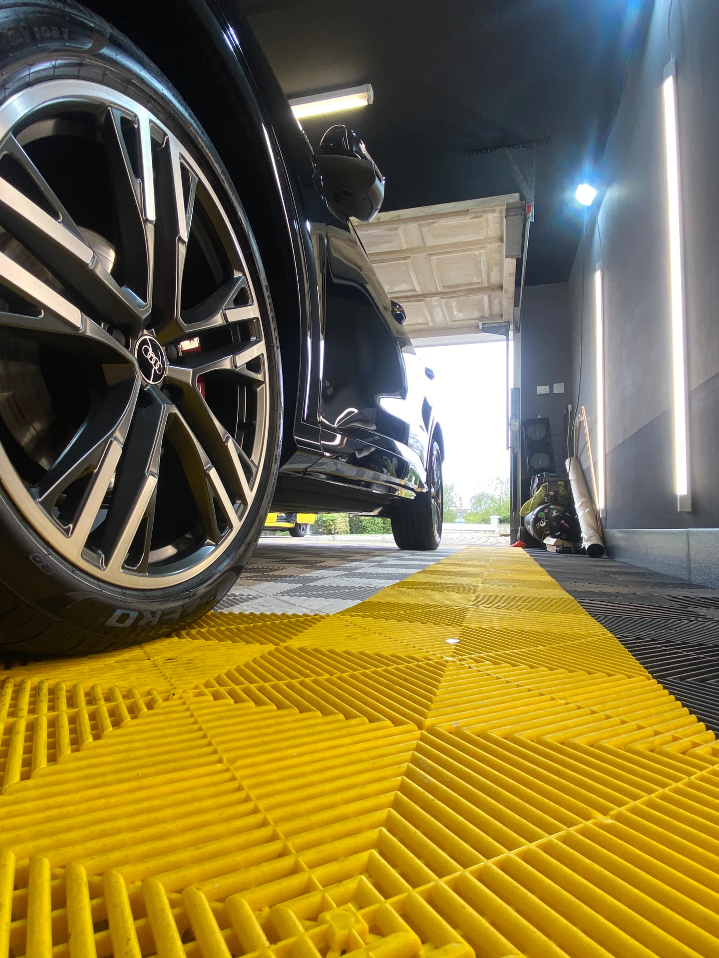 Low angle of a black Audi's polished alloy wheel and flank in the detailing unit