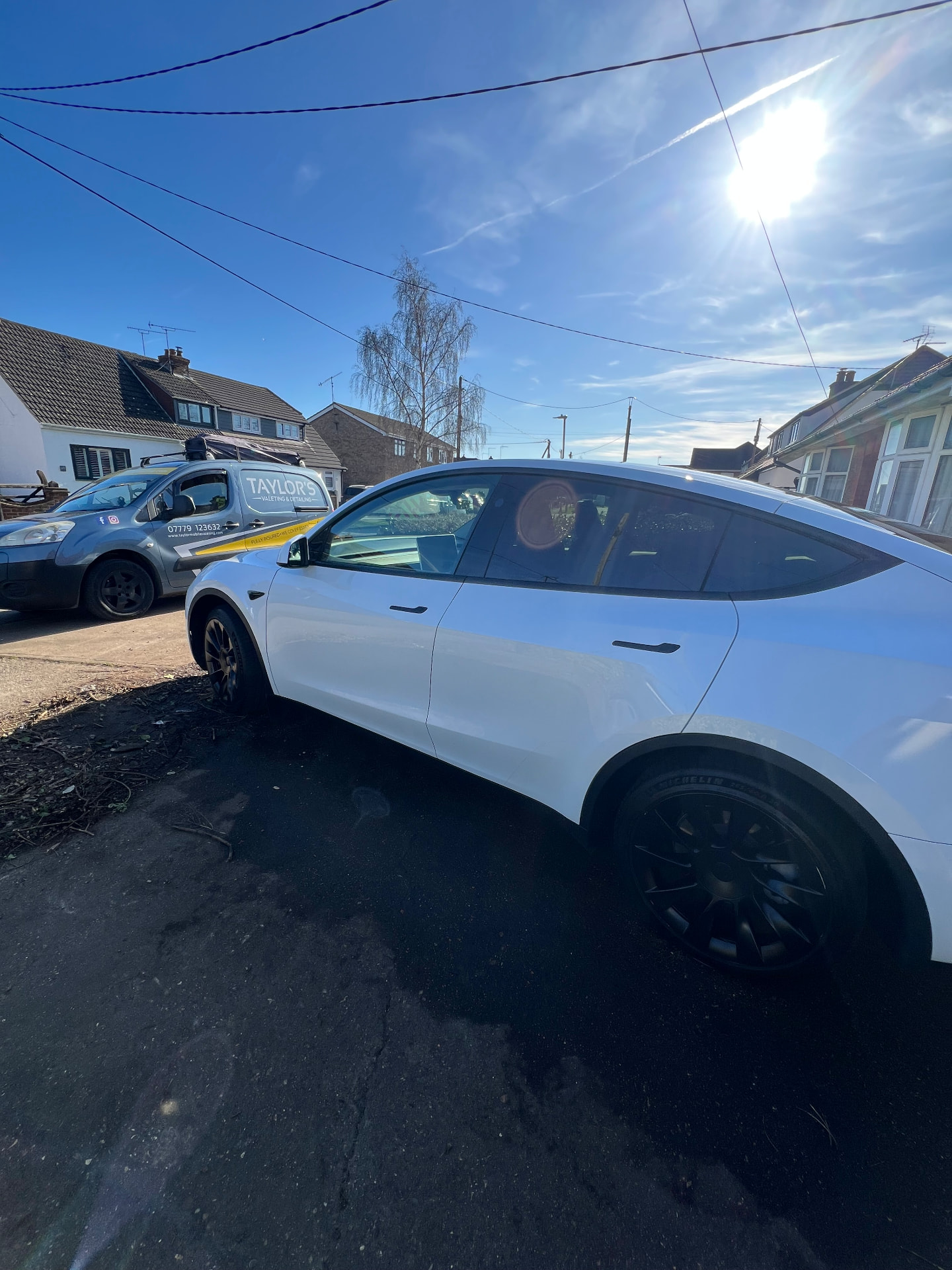 White Tesla Model Y valeted beside the Taylor's valeting van