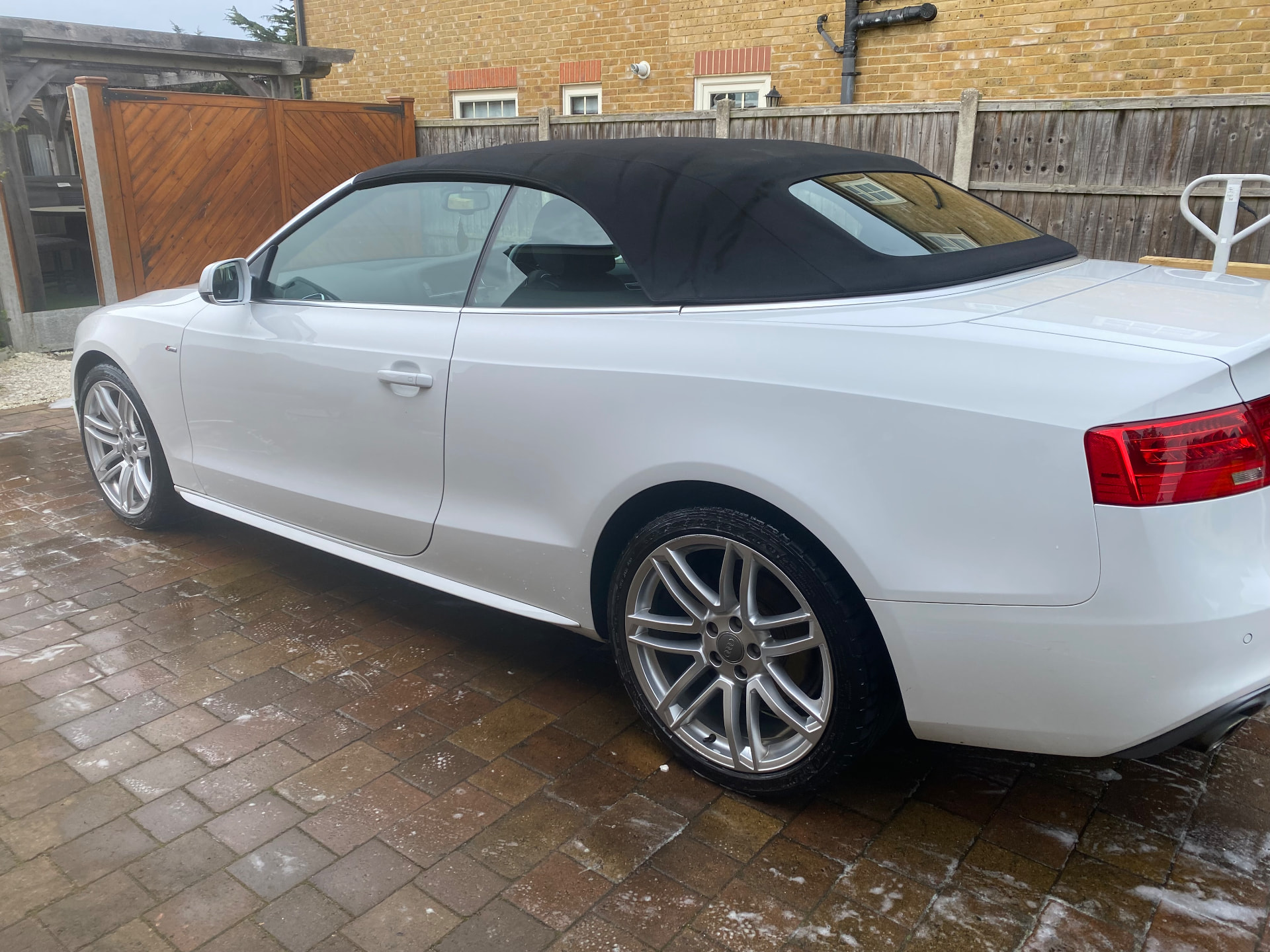 White Audi A5 S line cabriolet washed to a gloss finish on a block-paved driveway
